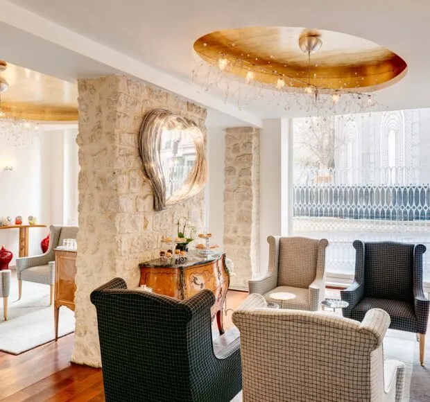 Vue du lobby de l’Hôtel 3 étoiles Lorette à Paris, où l’élégance des couleurs se marie harmonieusement avec le charme des murs en pierre historiques, créant une atmosphère raffinée
