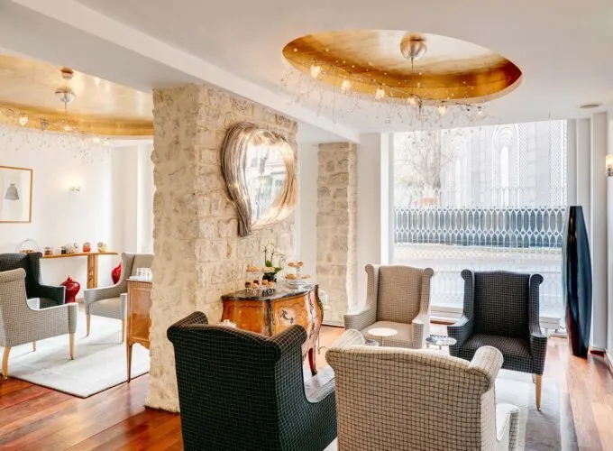 Vue du lobby de l’Hôtel 3 étoiles Lorette à Paris, où l’élégance des couleurs se marie harmonieusement avec le charme des murs en pierre historiques, créant une atmosphère raffinée