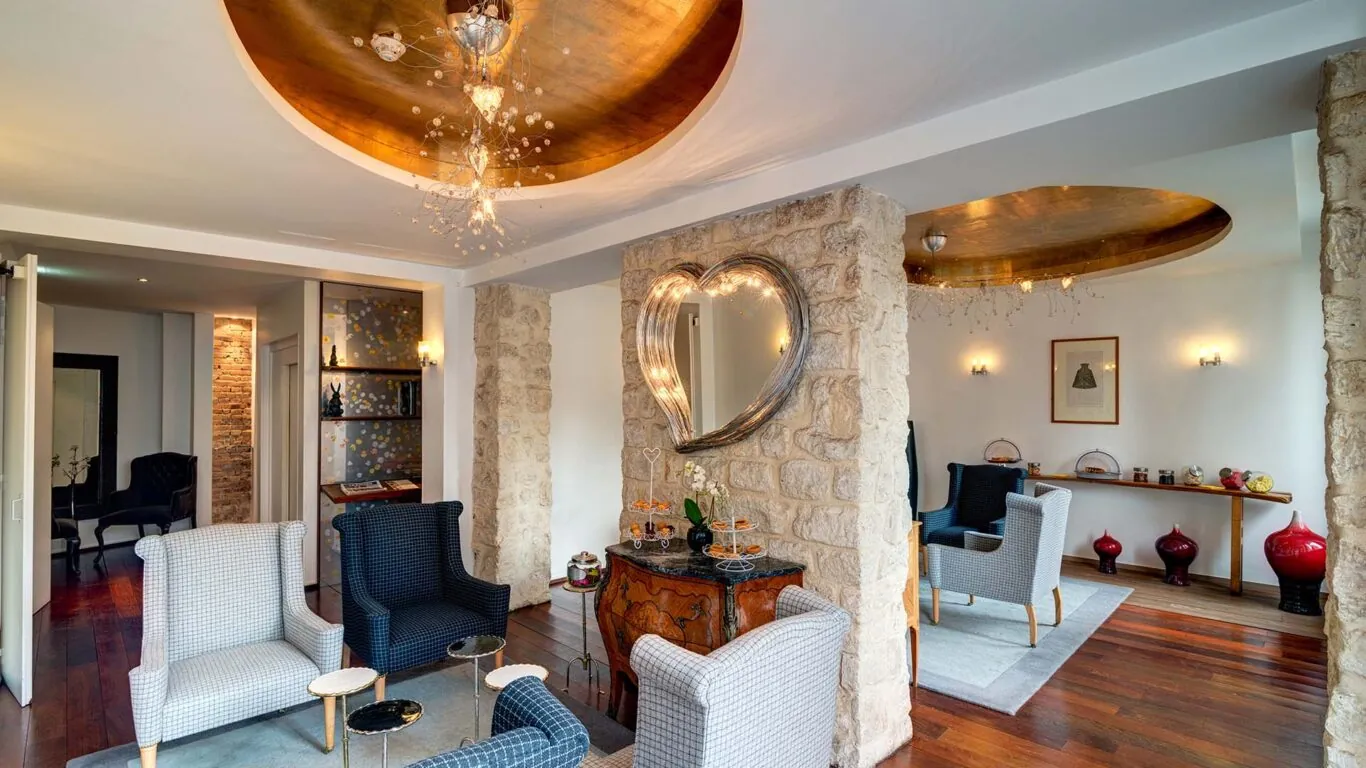 Lobby de l’Hôtel 3 étoiles Lorette à Paris avec des couleurs élégantes, des murs en pierre historiques et une atmosphère raffinée