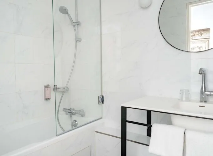 Salle de bain Duplex avec un miroir rond et une baignoire à l’Hôtel Malte