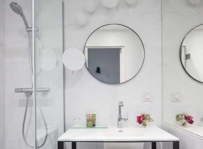 Salle de bain d’une chambre Single avec deux miroirs ronds et un lavabo à l’Hôtel Malte