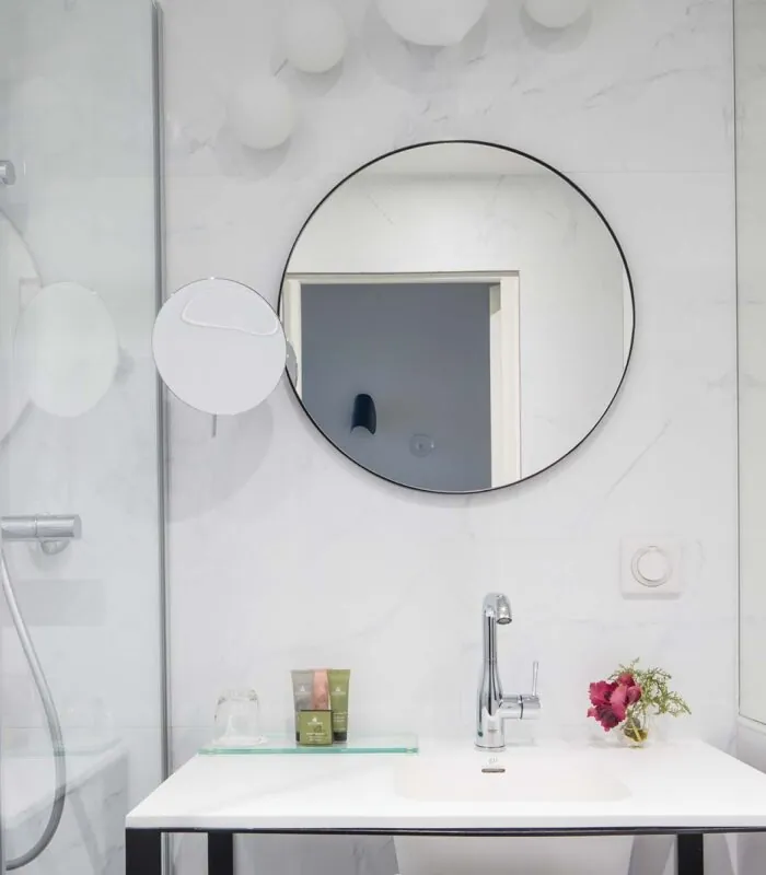 Salle de bain d’une chambre Single avec deux miroirs ronds et un lavabo à l’Hôtel Malte