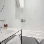 Salle de bain d’une chambre Privilège avec un lavabo, une baignoire et un miroir à l’Hôtel Malte