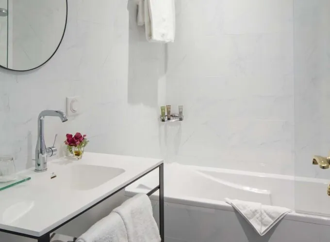 Salle de bain d’une chambre Privilège avec un lavabo, une baignoire et un miroir à l’Hôtel Malte