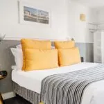 Lit d’une chambre Double avec des oreillers jaunes et une couverture à rayures à l’Hôtel Monterosa