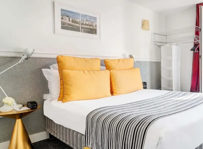 Lit d’une chambre Double avec des oreillers jaunes et une couverture à rayures à l’Hôtel Monterosa