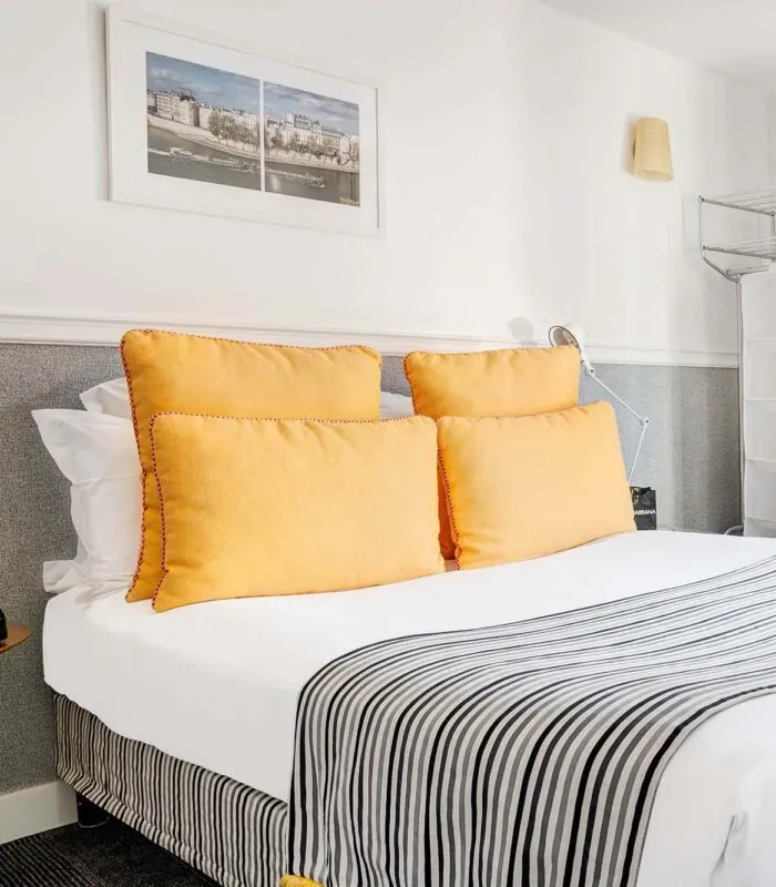 Lit d’une chambre Double avec des oreillers jaunes et une couverture à rayures à l’Hôtel Monterosa