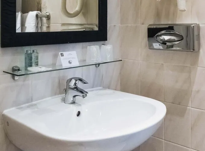 Lavabo de la salle de bain d’une chambre Single avec un panneau à l’Hôtel Monterosa