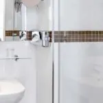 Salle de bain d’une chambre Single avec un lavabo, un miroir et une douche à l’Hôtel Monterosa