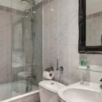 Salle de bain d’une chambre Twin avec du carrelage blanc et un miroir noir à l’Hôtel Monterosa