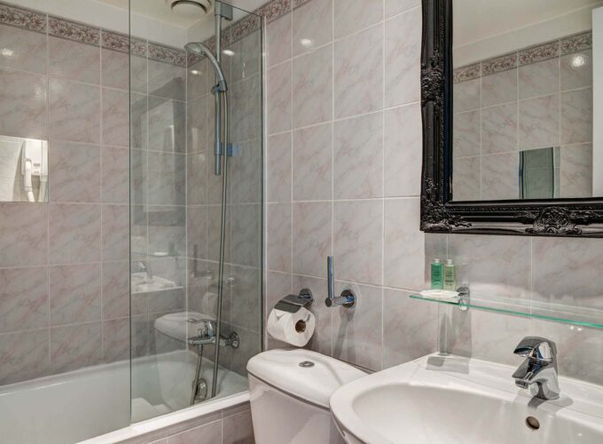 Salle de bain d’une chambre Twin avec du carrelage blanc et un miroir noir à l’Hôtel Monterosa