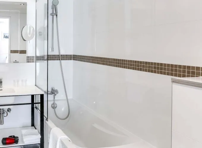 Salle de bain d’une chambre Twin avec une baignoire, un lavabo et un miroir à l’Hôtel Monterosa