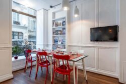 Salle de petit-déjeuner de l’hôtel 3 étoiles Monterosa du groupe Astotel à Paris, avec des chaises rouges et blanches, des tables en bois et une décoration murale sur le thème des livres
