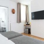 Chambre communicante avec deux lits et une télévision à écran plat à l’Hôtel Palm