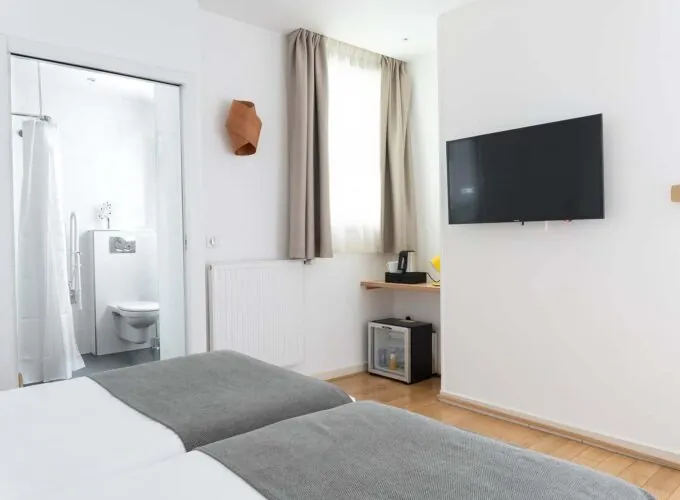 Chambre communicante avec deux lits et une télévision à écran plat à l’Hôtel Palm