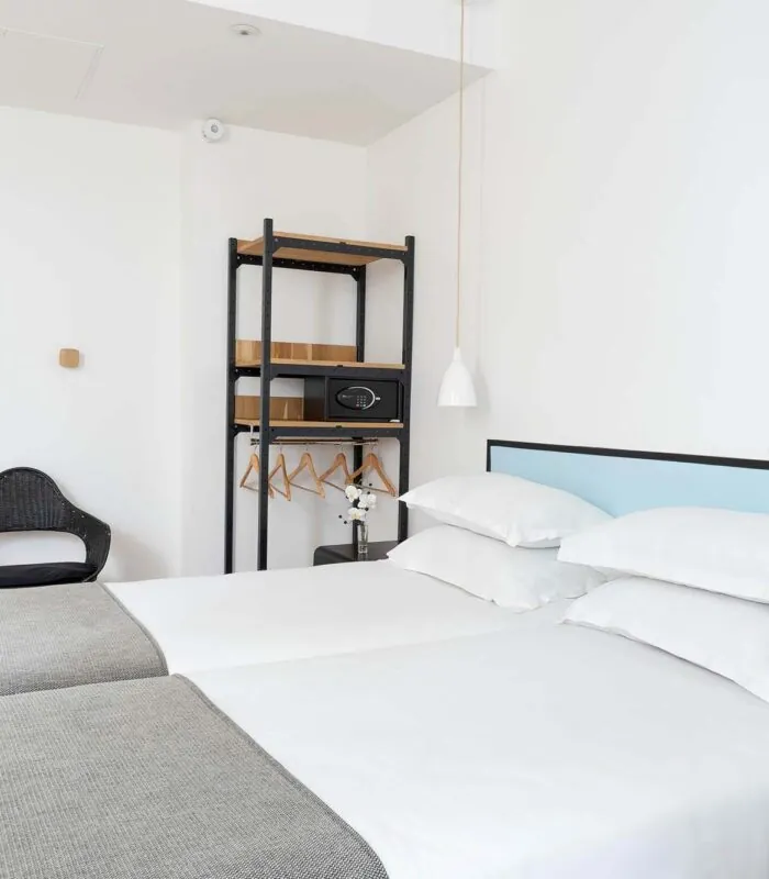 Une des 2 chambres de la chambre Communicante avec deux lits et une chaise en bois à l’Hôtel Palm