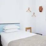 Une des 2 chambres de la chambre communicante avec un lit simple et une tête de lit bleue à l’Hôtel Palm