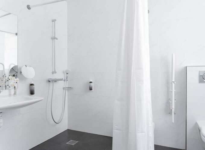 Salle de bain d’une des 2 chambres de la chambre communicante avec un rideau de douche blanc et un lavabo à l’Hôtel Palm