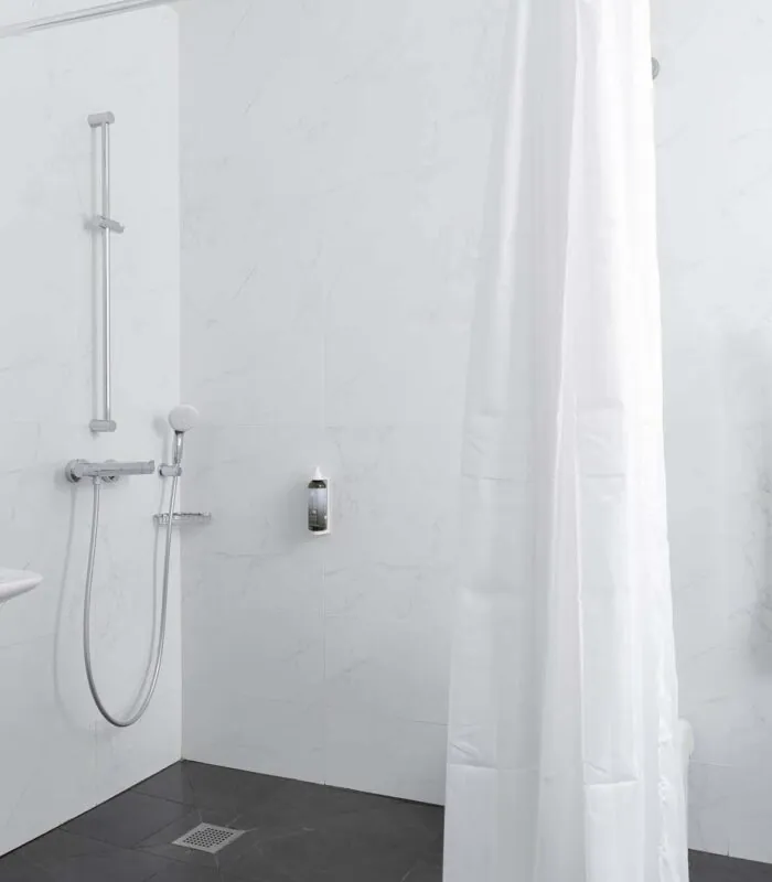 Salle de bain d’une des 2 chambres de la chambre communicante avec un rideau de douche blanc et un lavabo à l’Hôtel Palm