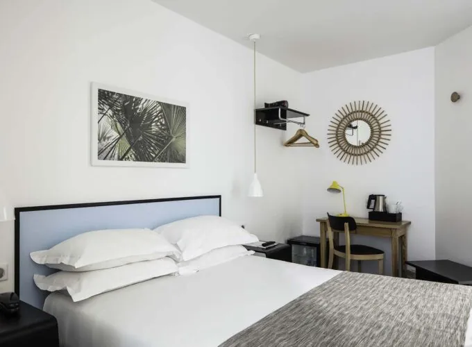 Chambre d’une chambre Double avec un miroir rond accroché au mur au-dessus d’un bureau à l’Hôtel Palm