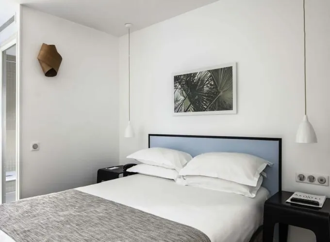 Chambre d’une chambre double avec un lit, une table de chevet et un tableau au mur à l’Hôtel Palm