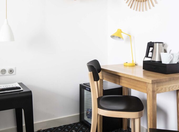 Bureau d’une chambre double avec une lampe jaune et une télécommande posée dessus à l’Hôtel Palm