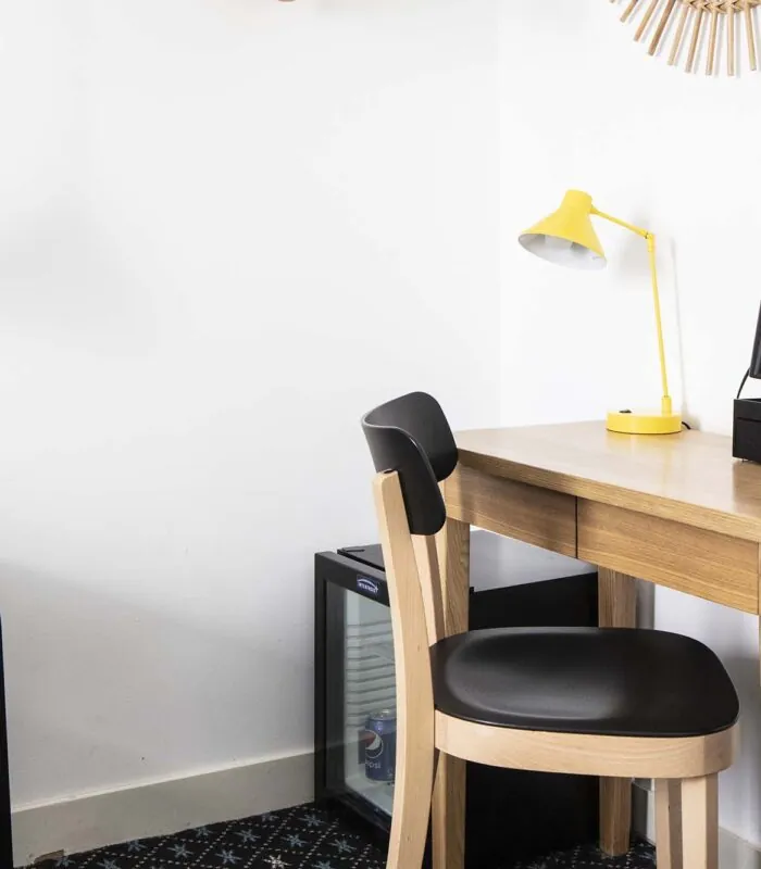 Bureau d’une chambre double avec une lampe jaune et une télécommande posée dessus à l’Hôtel Palm