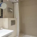 Salle de bain d’une chambre double avec un lavabo, un miroir et une douche à l’Hôtel Palm