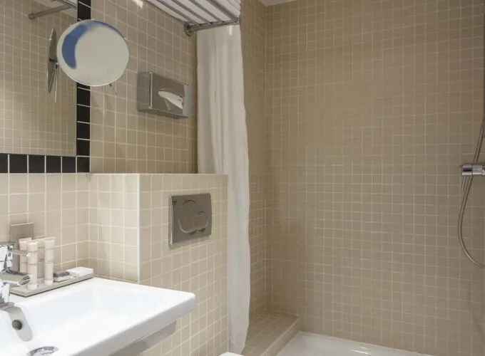 Salle de bain d’une chambre double avec un lavabo, un miroir et une douche à l’Hôtel Palm