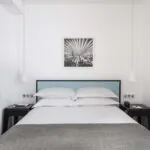 Une des 2 chambres de la chambre Familiale avec un tableau au mur au-dessus du lit à l’Hôtel Palm