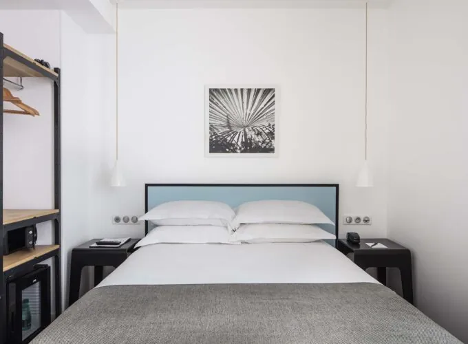 Une des 2 chambres de la chambre Familiale avec un tableau au mur au-dessus du lit à l’Hôtel Palm