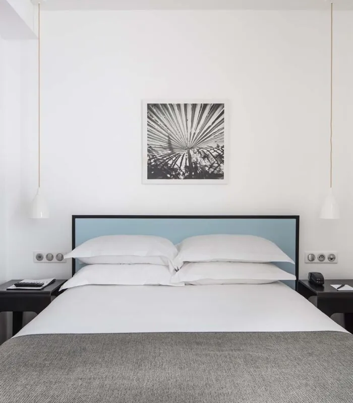 Une des 2 chambres de la chambre Familiale avec un tableau au mur au-dessus du lit à l’Hôtel Palm