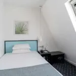 Chambre d’une chambre Single avec un lit simple et un tableau de palmier au mur à l’Hôtel Palm