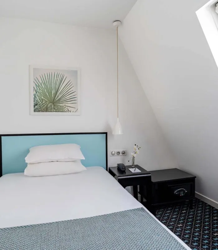 Chambre d’une chambre Single avec un lit simple et un tableau de palmier au mur à l’Hôtel Palm