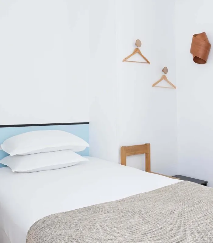 Chambre de la chambre Single Cocoon avec un lit simple et une tête de lit bleue à l’Hôtel Palm