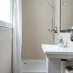 Salle de bain de la chambre Single Cocoon avec un lavabo, un miroir et une douche à l’Hôtel Palm