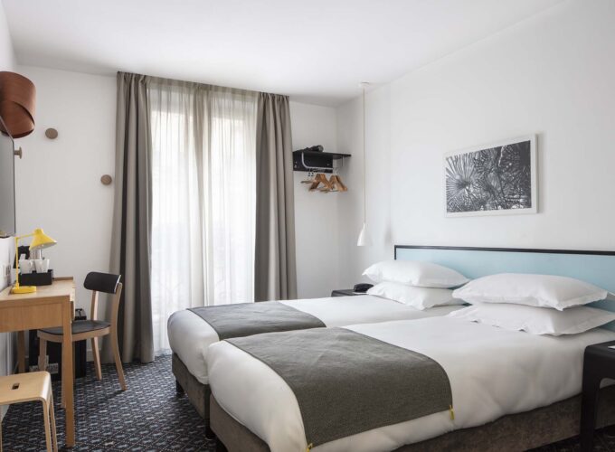 Chambre Twin avec deux lits et un bureau à l’Hôtel Palm