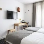 Chambre Twin avec deux lits, un bureau et une télévision à écran plat à l’Hôtel Palm