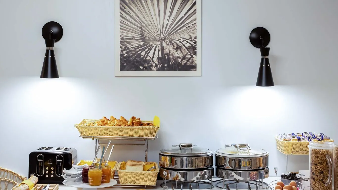 Petit-déjeuner buffet de l’Hôtel Palm à Paris avec viennoiseries, pains frais, fromages, charcuterie, yaourts, fruits frais et secs, et céréales