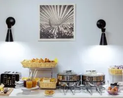 Petit-déjeuner buffet de l’Hôtel Palm à Paris avec viennoiseries, pains frais, fromages, charcuterie, yaourts, fruits frais et secs, et céréales