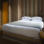 Chambre familiale supérieure vue Jardin avec un lit et une porte jaune à l’Hôtel Regent’s Garden