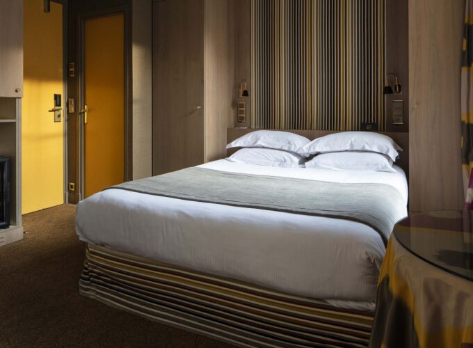 Chambre familiale supérieure vue Jardin avec un lit et une porte jaune à l’Hôtel Regent’s Garden