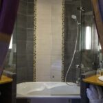 Salle de bain de la chambre familiale supérieure vue Jardin avec une baignoire et une douche à l’Hôtel Regent’s Garden