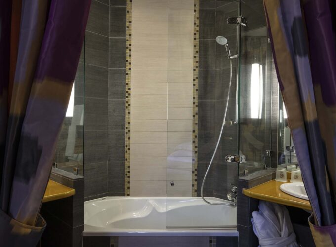 Salle de bain de la chambre familiale supérieure vue Jardin avec une baignoire et une douche à l’Hôtel Regent’s Garden