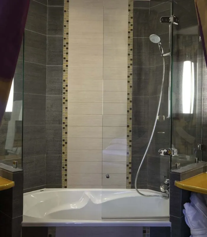 Salle de bain de la chambre familiale supérieure vue Jardin avec une baignoire et une douche à l’Hôtel Regent’s Garden