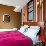 Chambre Privilège Vue Jardin avec deux lits et un miroir au mur à l’hôtel Regent’s Garden