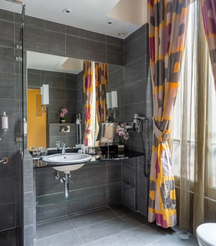 Salle de bain de la Chambre Twin Supérieure avec un lavabo et une fenêtre avec des rideaux colorés à l’hôtel Regent’s Garden