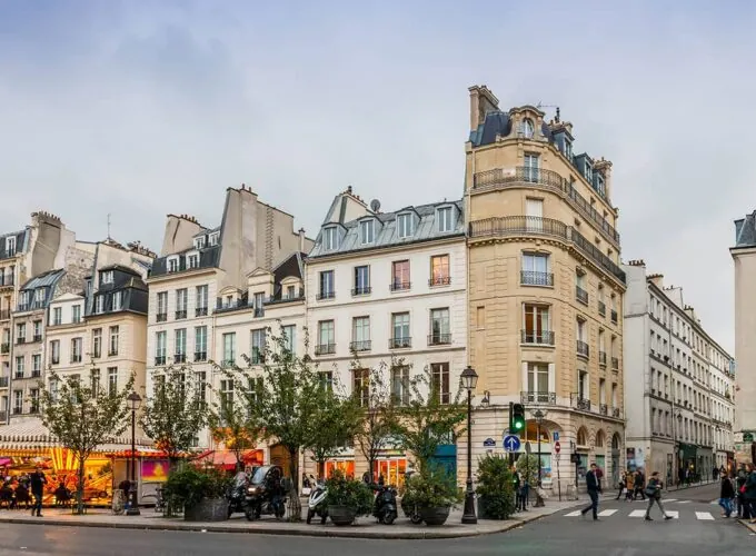 Scène de rue dans le quartier du Marais à Paris, avec façades typiques et vie de quartier parisienne.