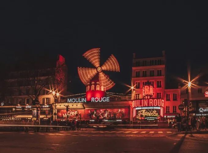 Le Moulin Rouge illuminé la nuit à Paris, cabaret historique de Pigalle avec son célèbre moulin rouge en façade.