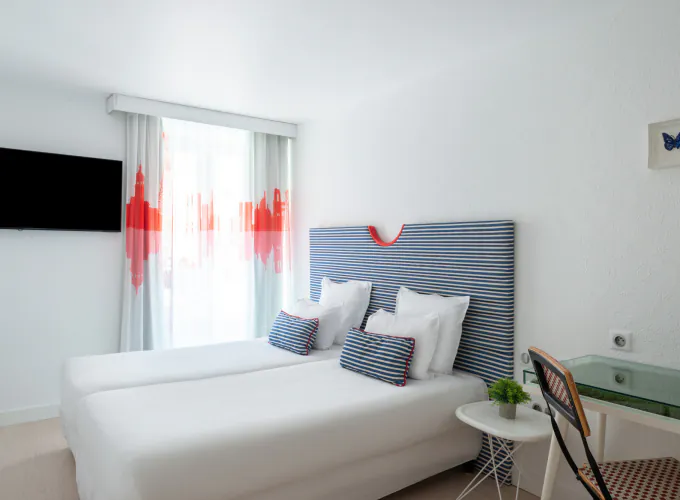 Chambre twin avec deux lits et une télévision à écran plat à l’Hôtel 34B